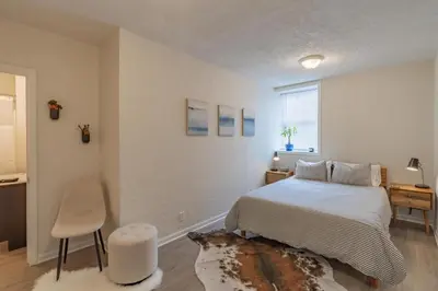 a bedroom with a bed and a table and a chair at University Suite 