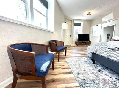 a bedroom with a bed and chairs and a television at University Suite 