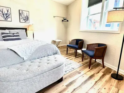 a bedroom with a bed and two chairs and a window at University Suite 
