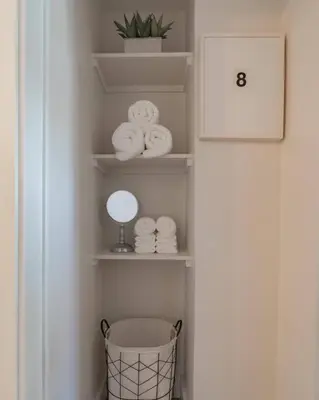 a bathroom with white shelves with towels and a mirror at Lodge On Landess in Marion
