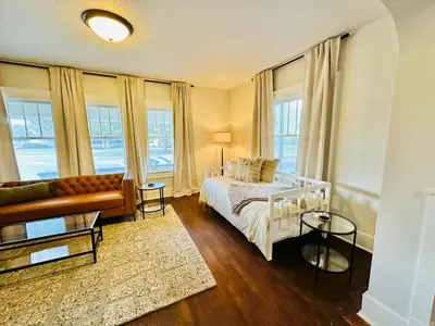 a bedroom with a bed and a couch and windows at Campus Haven in Kiley