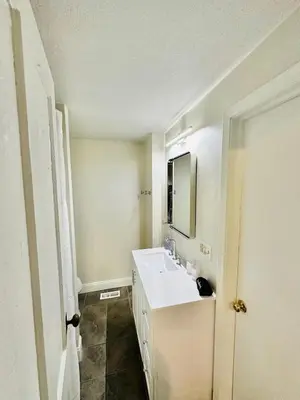 a white bathroom with a sink and a mirror at Campus Haven in Kiley
