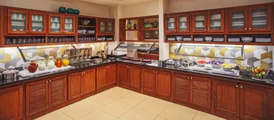 a large kitchen with wooden cabinets and food on display at Hyatt Place Cincinnati Blue Ash in Blue Ash
