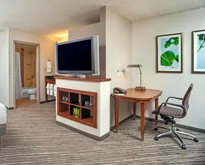 a hotel room with a television and a desk and a chair at Hyatt Place Cincinnati Blue Ash in Blue Ash