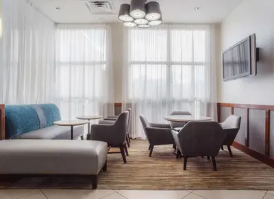 a waiting room with tables and chairs and windows at Hyatt Place Cincinnati Blue Ash in Blue Ash