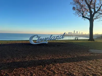 a sign in a park with the city in the background at StayWithJay Premium Furnished Room near Cleveland Airport in Cleveland