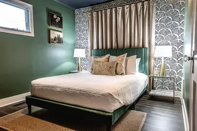 a bedroom with a bed with green walls and two lamps at Fauver Suite in Dayton