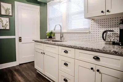 a kitchen with white cabinets and a sink at Fauver Suite in Dayton