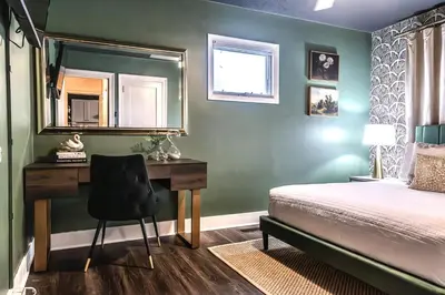 a bedroom with a bed and a desk with a mirror at Fauver Suite in Dayton
