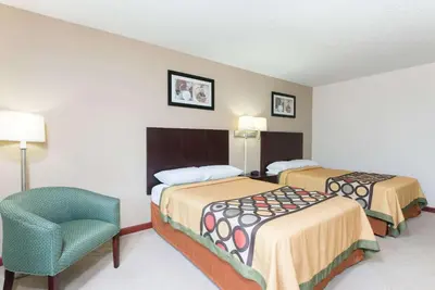 a hotel room with two beds and a chair at Super 8 by Wyndham Beaver Falls in Beaver Falls
