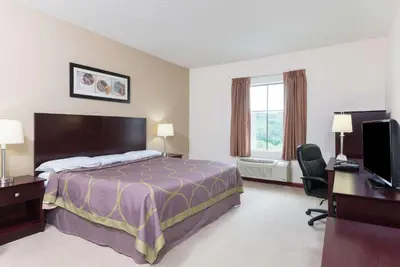 a hotel room with a bed and a desk and a computer at Super 8 by Wyndham Beaver Falls in Beaver Falls