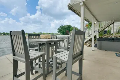 a table and chairs sitting on a porch next to the water at Hot Tub and Dock Waterfront Lake Hamilton Home in Hamilton