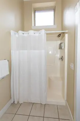 a bathroom with a shower with a white shower curtain at The Jazz Club Downtown Sandusky in Sandusky