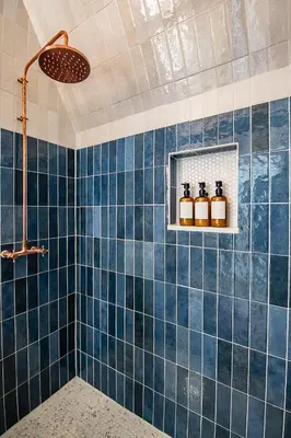 a blue tiled bathroom with three bottles on a shelf at Cherry Hollow in McArthur