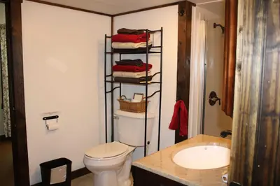 a bathroom with a toilet and a shelf with towels at East Fork Acres in Logan
