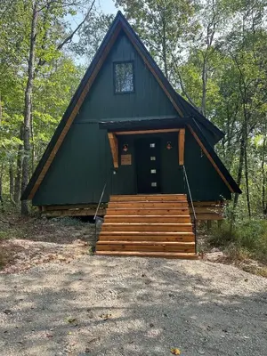 a large green building with a porch and a door at Hickory Hollow in McArthur