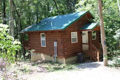 a small wooden cabin in the woods with a porch at Jack Pine Hollow in Logan