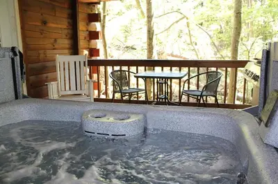 a hot tub on a deck with a table and chairs at Jack Pine Hollow in Logan