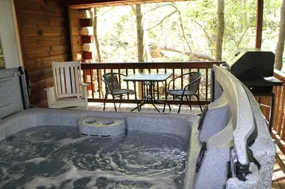 a hot tub on a deck with a table and chairs at Jack Pine Hollow in Logan