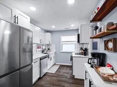 a kitchen with white cabinets and a stainless steel refrigerator at Modern 3Bed Home Near CLE With Private Backyard in Parma Heights