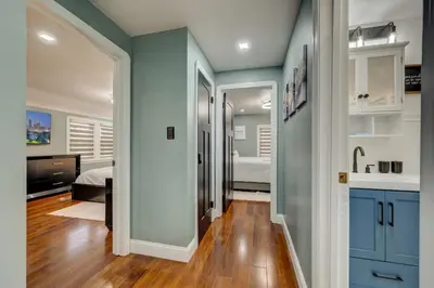 a bathroom with blue cabinets and a bedroom with a bed at South Euclid Home 10 Minutes to Cleveland Clinic in South Euclid