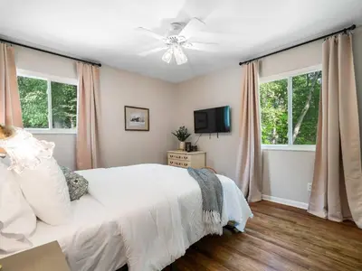a bedroom with a bed with a ceiling fan and windows at Large Remodeled 4 Bed 3 Bath Secluded With Hot Tub in Akron