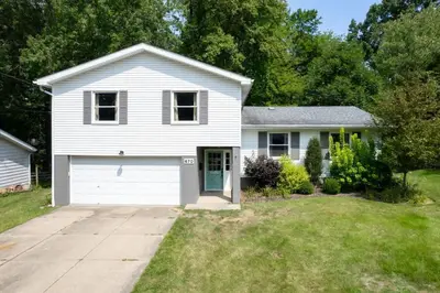 a white house with a garage in a yard at Large Remodeled 4 Bed 3 Bath Secluded With Hot Tub in Akron