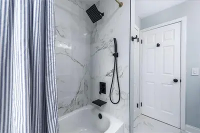 a white bathroom with a shower and a tub at Hot Tub Game Room with Shuffleboard N64 Sleeps 8 in Parma Heights