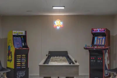 two arcade machines sitting next to each other in a room at Hot Tub Game Room with Shuffleboard N64 Sleeps 8 in Parma Heights