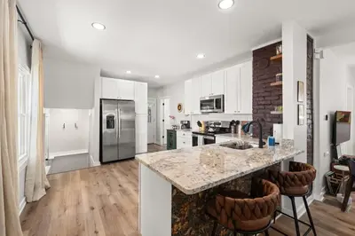 a kitchen with white cabinets and a kitchen island with bar stools at Renovated and Professionally Designed 3Bed Home in Euclid