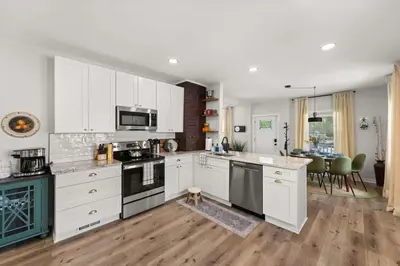 a kitchen with white cabinets and appliances and a dining room at Renovated and Professionally Designed 3Bed Home in Euclid