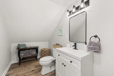 a white bathroom with a toilet and a mirror at Renovated and Professionally Designed 3Bed Home in Euclid