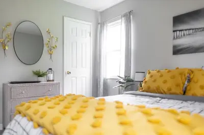 a bedroom with a bed with a yellow comforter and a mirror at Entire Secluded House Close To CLE Airport and BWU in Strongsville