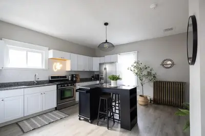 a kitchen with white cabinets and a black island at Large Renovated 4 Bedroom Home 9 min to Downtown CLE in Cleveland