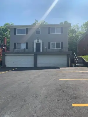 a large house with a garage in a parking lot at Cozy Retreat Apartment in Cincinnati