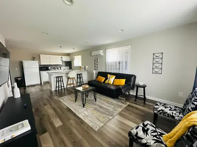 a living room with a black couch and a kitchen at Reading-Stylish Apartment for Contemporary Comfort in Cincinnati