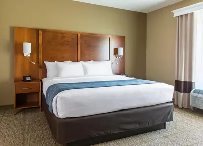 a bedroom with a large bed with a wooden headboard at Comfort Suites Hartville-North Canton in Uniontown