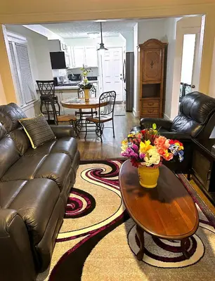 a living room with a leather couch and a table with flowers at LOVELY FURNISHED HOUSE FOR rent in Akron