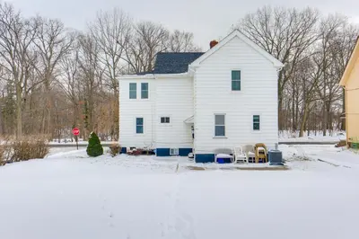 a white house with a stop sign in the snow at 11 Mi to Dtwn Cleveland Family Home with Yard in Garfield Heights