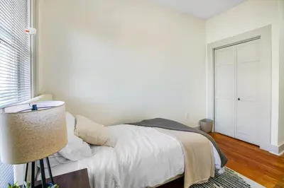 a white bedroom with a bed and a lamp at Victorian Cozy Retreat Steps to Cleveland Clinic in Cleveland
