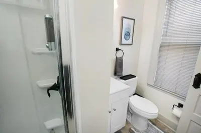 a white bathroom with a toilet and a window at Victorian Cozy Retreat Steps to Cleveland Clinic in Cleveland