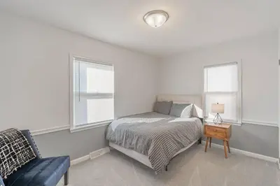 a bedroom with a bed and a chair and two windows at The Ranch on RaceStreet in Marion