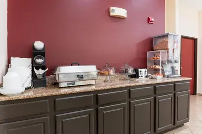 a kitchen with a counter top with a red wall at Red Roof Inn Carrollton in Carrollton