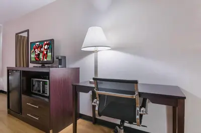 a desk with a chair and a tv and a lamp at Red Roof Inn Carrollton in Carrollton