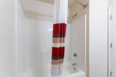 a bathroom with a red and white shower curtain at Red Roof Inn Carrollton in Carrollton