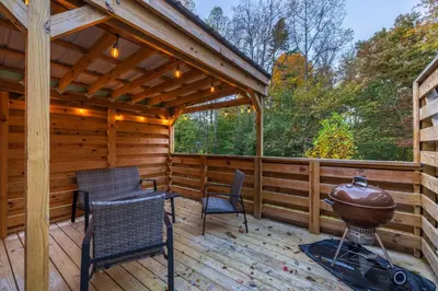 a cabin with a grill and chairs on a deck at New listing-- Hocking Hills Modern Cabin in Logan