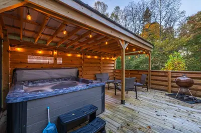 a covered deck with a bed and a grill at New listing-- Hocking Hills Modern Cabin in Logan
