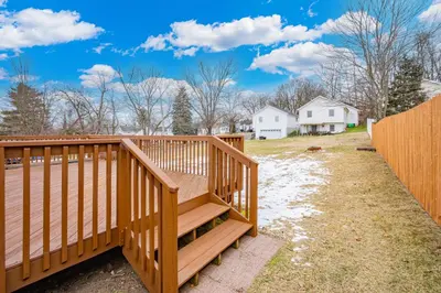 a wooden ramp leading to a deck with a house in the background at Comfort Awaits at Cozy Get Away - Dog Friendly in Akron