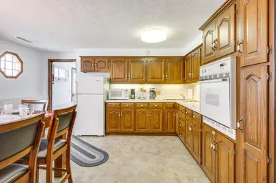 a kitchen with wooden cabinets and white appliances at Secluded Ohio Amish Country Getaway with Fire Pit in Sugarcreek