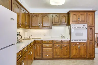 a kitchen with wooden cabinets and white appliances at Secluded Ohio Amish Country Getaway with Fire Pit in Sugarcreek